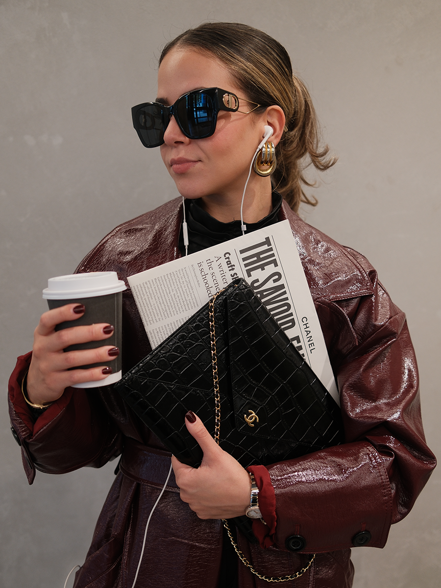 Woman styling a black Chanel bag with coffee and newspaper